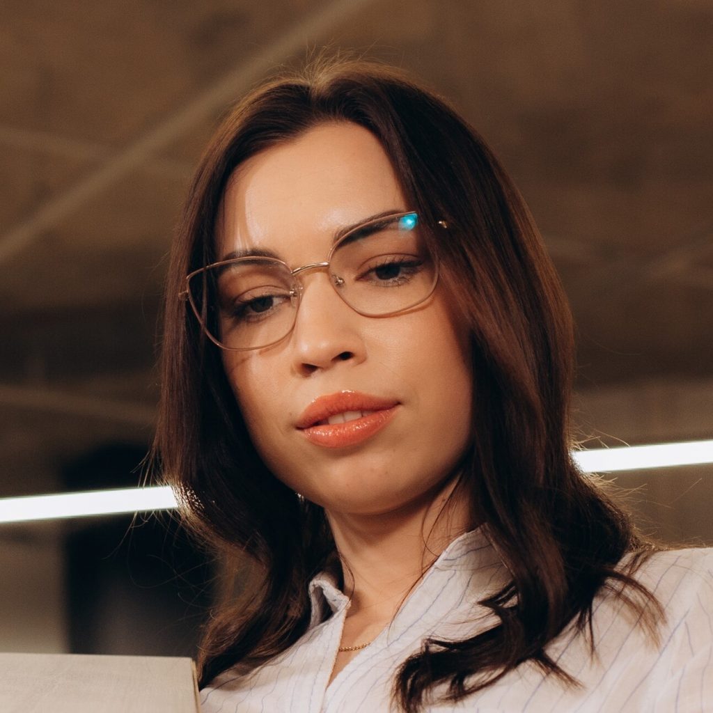 Retrato de Hana Expósito, arquitecta, examinando planos en su lugar de trabajo.