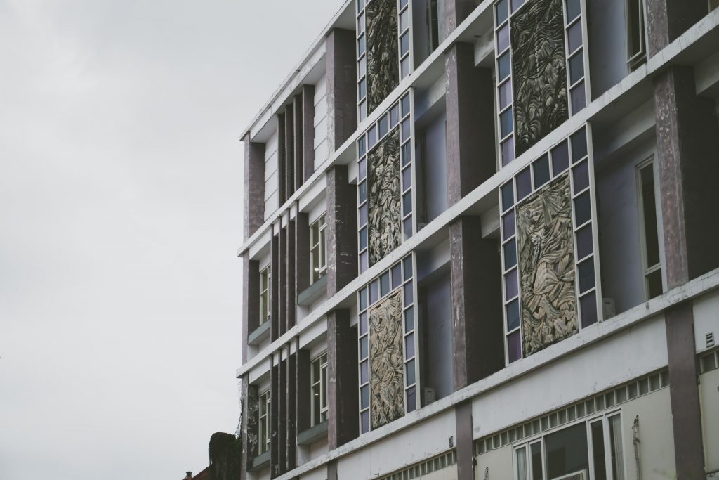 Fachada de un edificio comercial con detalles artísticos y signos de desgaste, ideal para empresas de rehabilitación de fachadas.
