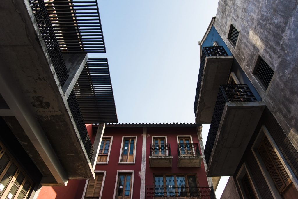 Vista desde abajo de fachadas de edificios urbanos con balcones y estructuras modernas, representando el trabajo de empresas de rehabilitación de fachadas.